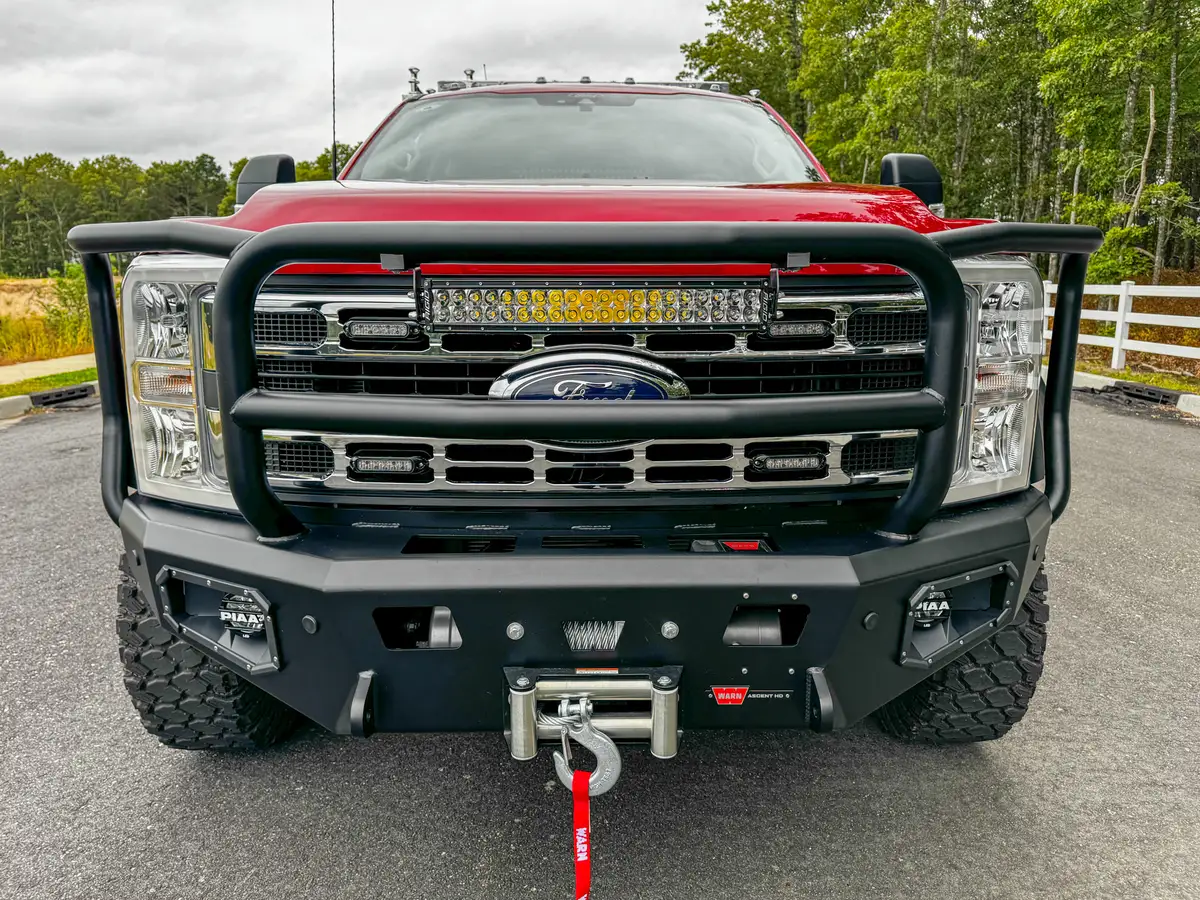 Front grille close-up from low angle with emblem and guard rail.